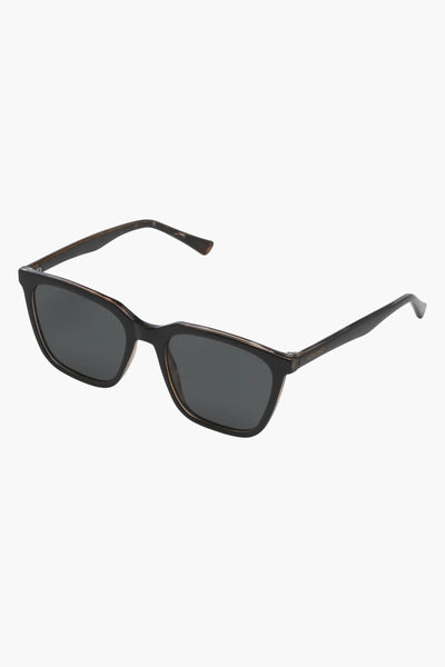 Lunettes de soleil noires de KOMONO, monture rectangulaire sombre et finie avec des détails écaille de tortue.