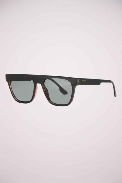 Lunettes de soleil noires de KOMONO, avec une monture épaisse et verres gris.