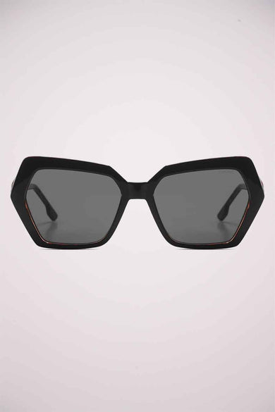 Lunettes de soleil noires de KOMONO, avec une monture géométrique épaisse et des verres teintés gris.
