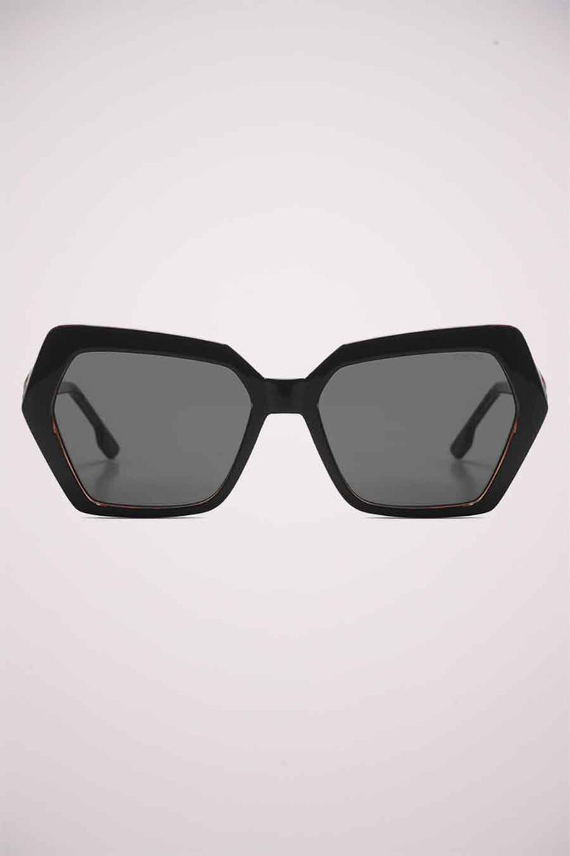 Lunettes de soleil noires de KOMONO, avec une monture géométrique épaisse et des verres teintés gris.
