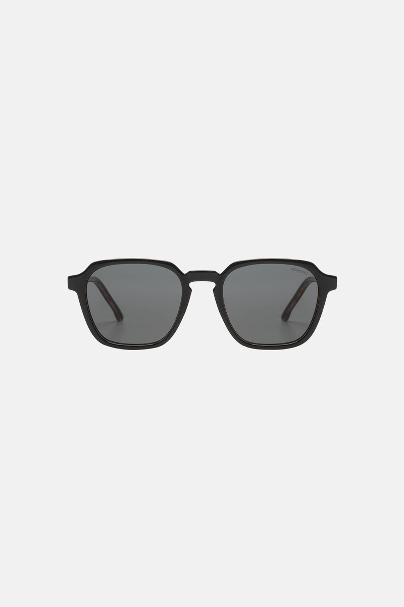 Lunettes de soleil noires de Komono, monture carrée et verres teintés unis.