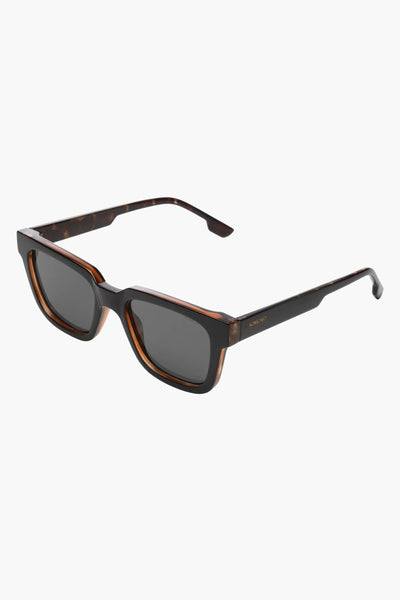 Lunettes de soleil noires de KOMONO, monture à motif écaille marron et noire, verres gris fumé.