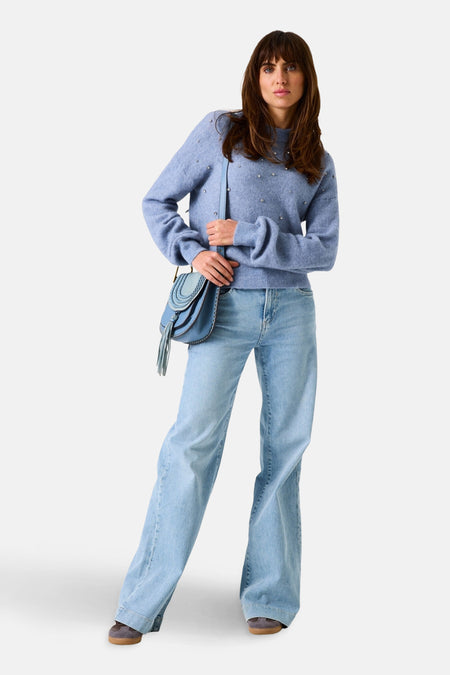 Pull bleu en maille par GARCIA avec des détails brillants, porté avec un jean décontracté et un sac à bandoulière assorti.