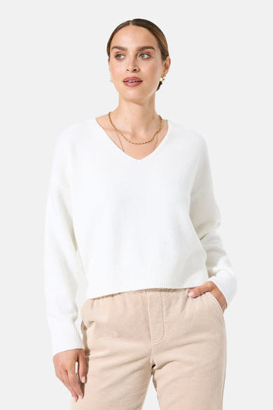 Pull col V blanc de GARCIA, porté avec un pantalon en velours côtelé et un collier doré.
