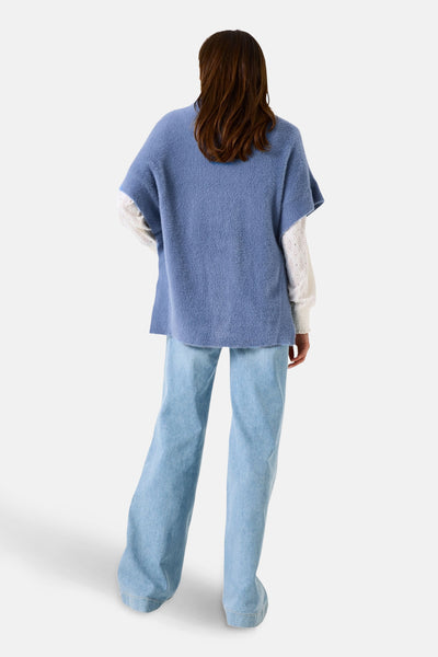 Blauwe tanktop van GARCIA in bouclébrei, gedragen over een witte blouse met lange mouwen, met een lichtblauwe wijde jeans.