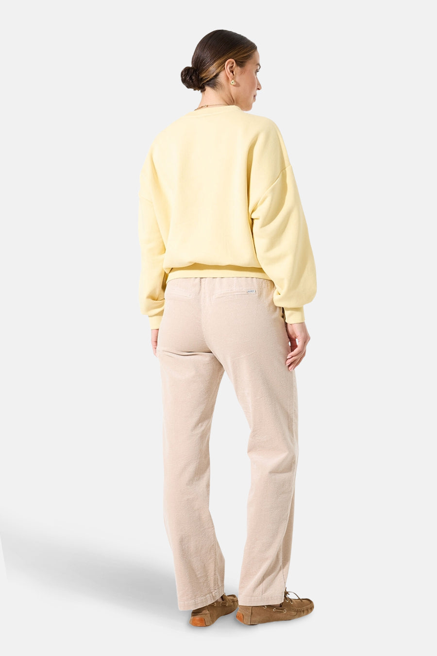 Sweat col rond jaune de GARCIA, porté avec un pantalon beige en velours côtelé et des chaussures bateau marron.