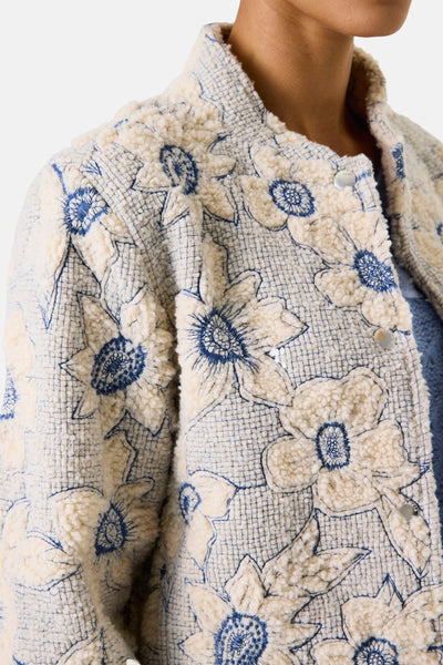 Kort bloemenjasje van GARCIA, met een blauw bloemenpatroon op een ecru getextureerde achtergrond.