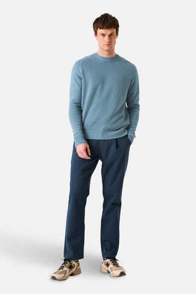 Pull col rond bleu de GARCIA, porté avec un pantalon bleu marine et des chaussures de sport multicolores.