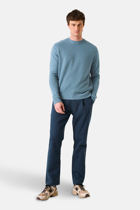 Pull col rond bleu de GARCIA, porté avec un pantalon bleu marine et des chaussures de sport multicolores.