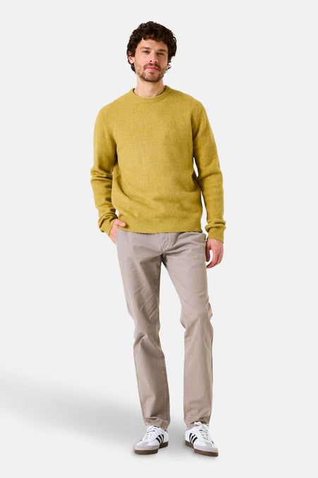 Pull col rond jaune de GARCIA, porté avec un pantalon beige et des chaussures de sport blanches à rayures noires.
