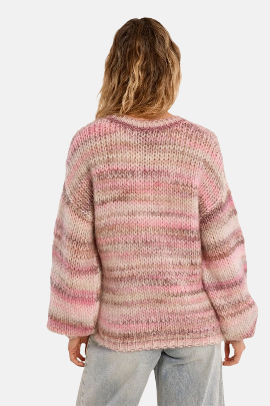Multicolored oversized knit sweater with pink and beige striped pattern, back view, worn with light blue jeans