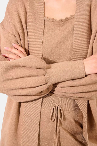 Gilet beige de Molly Bracken, avec manches bouffantes et texture tricotée, porté avec un haut assorti.