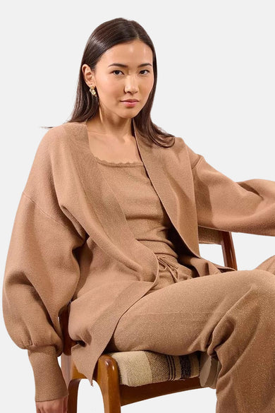 Beige gilet van Molly Bracken, gedragen met een bijpassend topje en broek, op een houten stoel.
