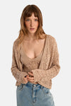 Gilet beige de Molly Bracken, en maille ajourée, porté avec un top et un jean taille haute.
