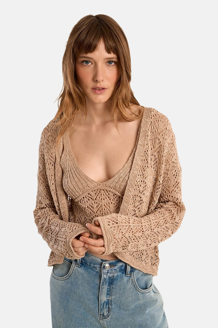 Gilet beige de Molly Bracken, en maille ajourée, porté avec un top et un jean taille haute.