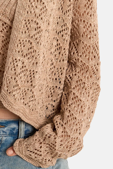 Gilet beige en maille ajourée de Molly Bracken, porté avec un jean bleu, coupe courte.
