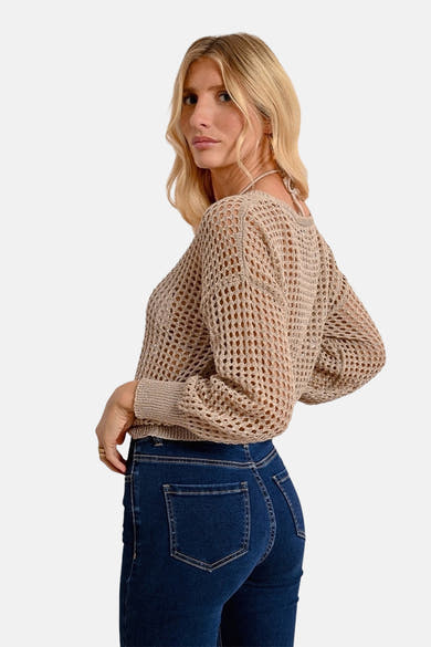 Beige V-hals trui van Molly Bracken, in ajour gebreid, gedragen met een donkerblauwe jeans.