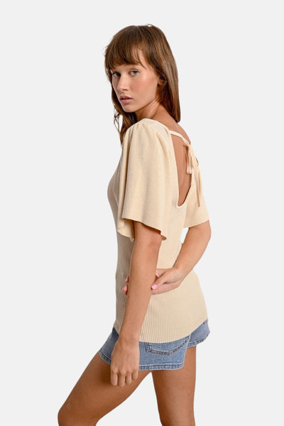 T-shirt écru à manches courtes de Molly Bracken avec dos nu noué et texture côtelée, porté avec un short en jean.