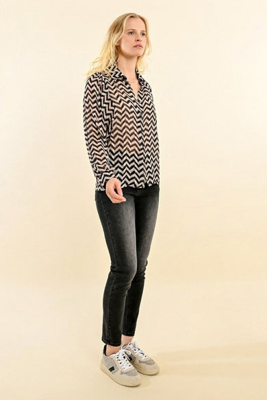 Chemisier noir à manches longues de Molly Bracken, motif zigzag, porté avec un jean gris et des baskets.