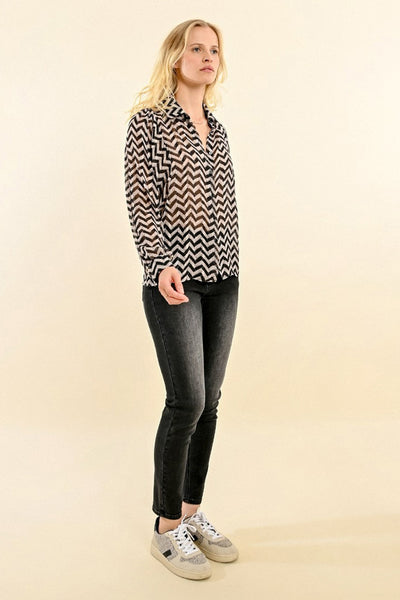 Chemisier noir à manches longues de Molly Bracken, motif zigzag, porté avec un jean gris et des baskets.
