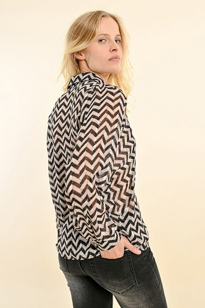 Zwarte blouse met lange mouwen van Molly Bracken, met zwart-wit chevronpatroon en een zwarte jeans.