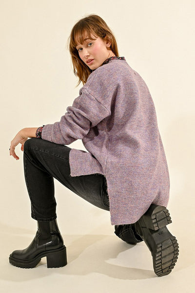 Pull violet à col rond de Molly Bracken, porté avec un jean noir et des bottes noires à semelles épaisses.
