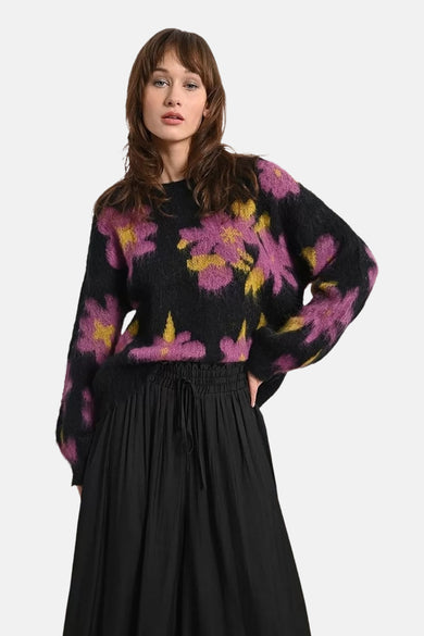 Multikleuren rondehals trui van Molly Bracken, met roze en geel bloemenpatroon, gedragen met een zwarte wijde rok.