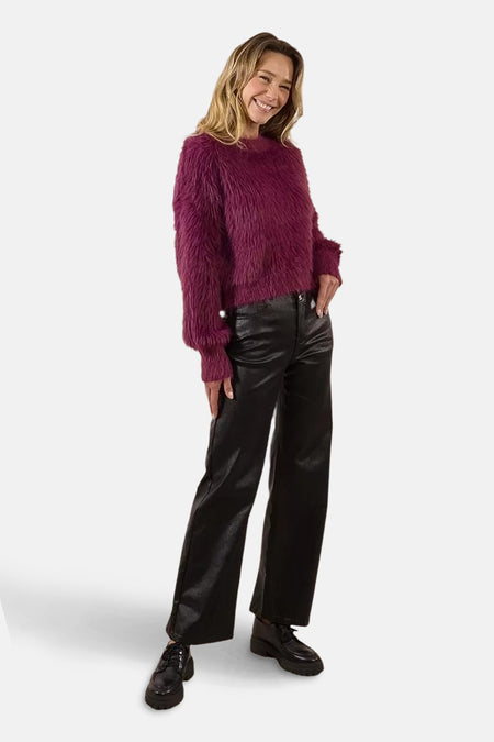 Paarse trui met ronde hals van Molly Bracken, gedragen met een imitatielederen broek en zwarte schoenen.
