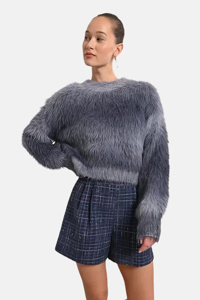 Ronde hals trui blauw Molly Bracken, van pluizige imitatiebont, gedragen met een geruite short met hoge taille.