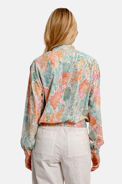 Korte meerkleurige jas van Molly Bracken, met slangenprint en elastische afwerkingen, gedragen met een witte broek.
