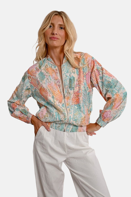 Korte meerkleurige jas van Molly Bracken met slangenprint en witte broek.