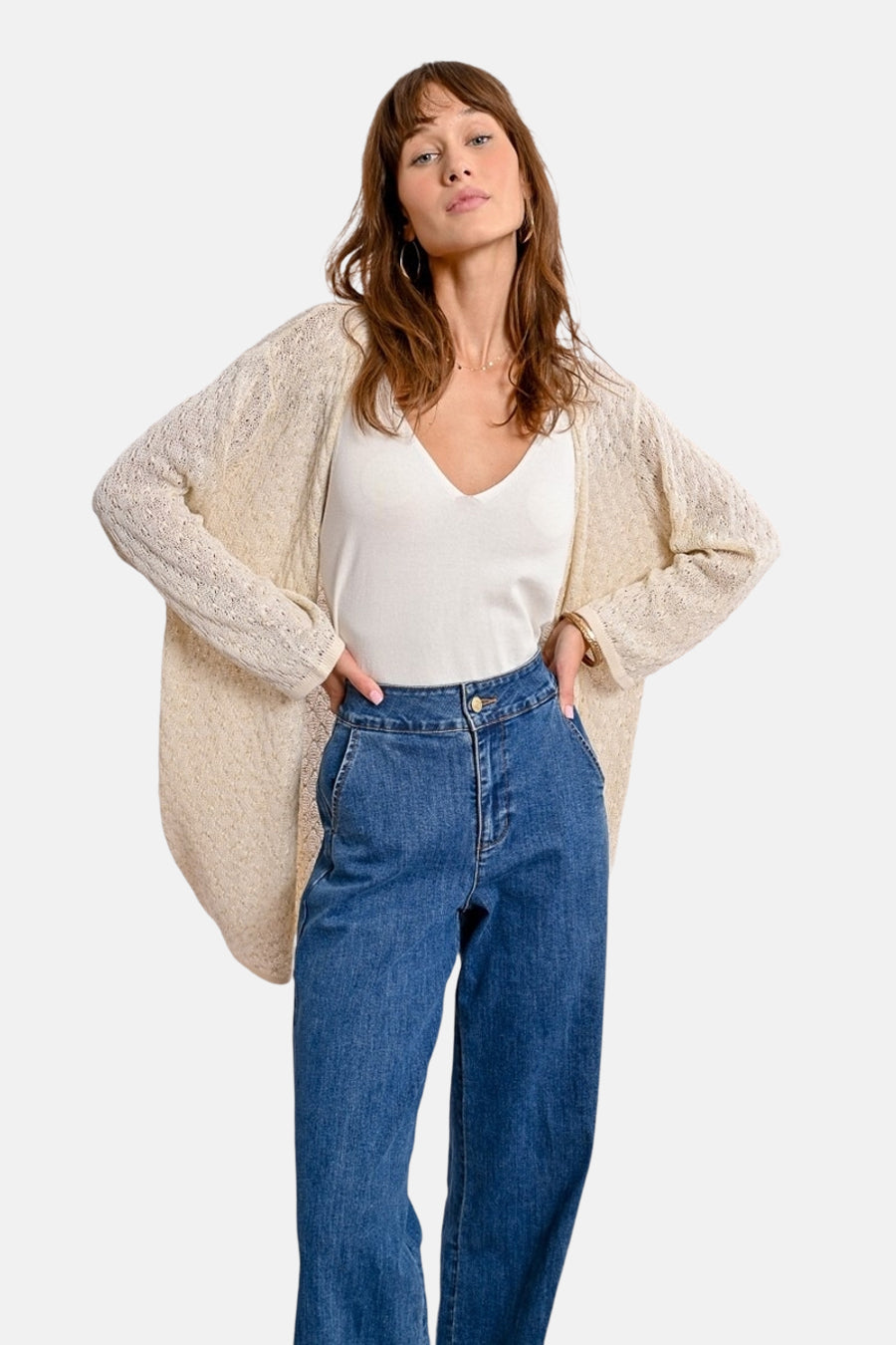 Ecru vest in openwork knit by Molly Bracken, worn over a white tank top and high-waisted jeans.