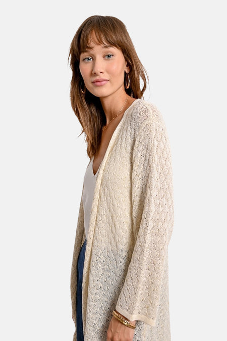 Ecru lange vest in open gebreide stof van Molly Bracken, gedragen over een witte tanktop met een spijkerbroek.