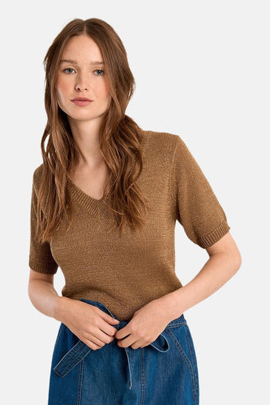 Pull col V cognac de Molly Bracken, en maille brillante, porté avec une jupe en denim bleu.