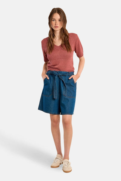 Pull col V rouge de Molly Bracken, porté avec un short en jean taille haute à ceinture nouée.