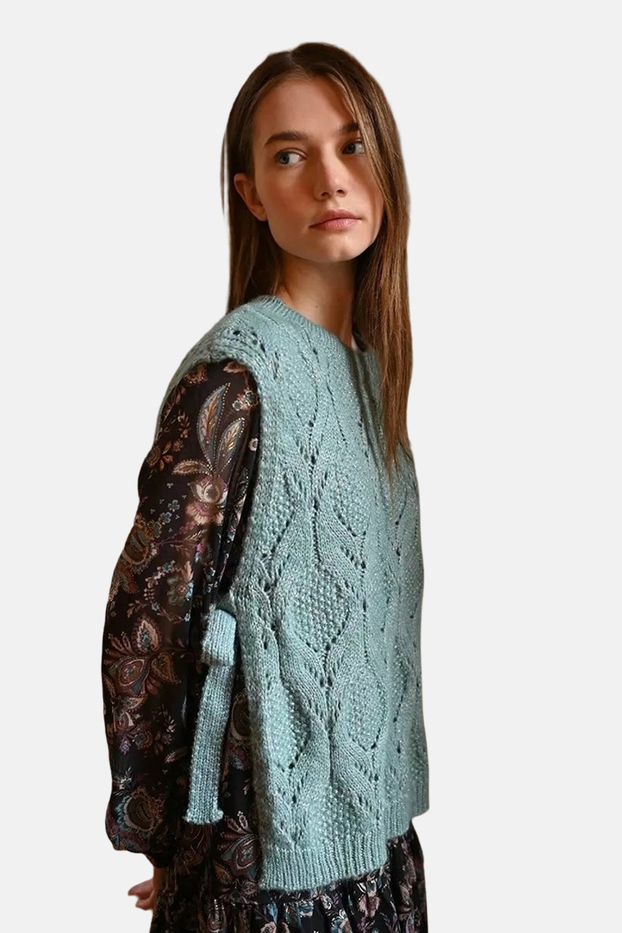 Blauwe tanktop van Molly Bracken, met ajourpatroon, gedragen over een donker bloemenjurk.