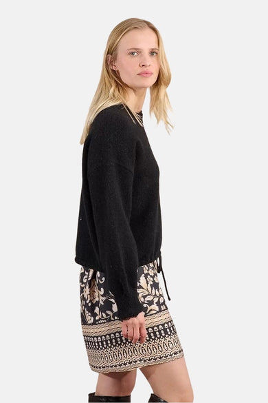 Pull noir à col rond de Molly Bracken, porté avec une jupe imprimée.