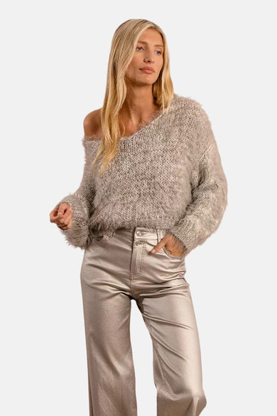 Grijze V-hals trui van Molly Bracken, gedragen met een glanzende broek met hoge taille.
