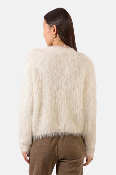 Cardigan écru du Molly Bracken, en fausse fourrure douce, porté avec un pantalon côtelé marron, vue de dos.