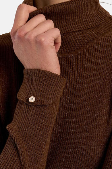 Zoom sur le col montant et la manche boutonnée d’un pull brun côtelé Molly Bracken.