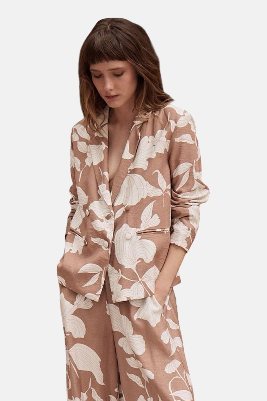 Multikleurige blazer van Molly Bracken met wit bloemenpatroon op een roze-beige achtergrond, gedragen met bijpassende broek.