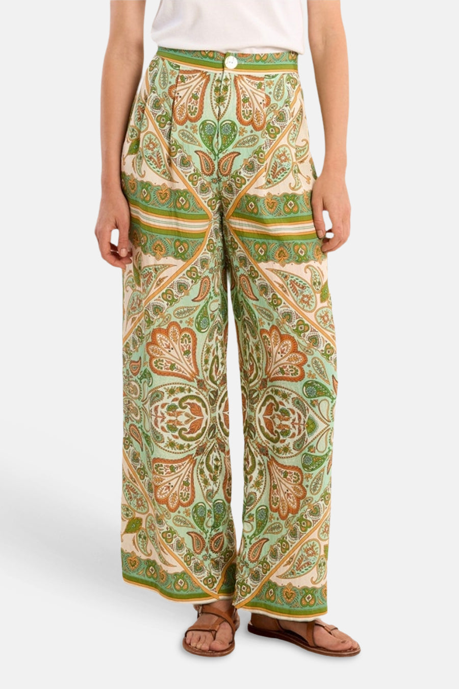 Pantalon large multicolore de Molly Bracken à motif cachemire et géométrique vert, orange et crème, porté avec un t-shirt blanc et des sandales.
