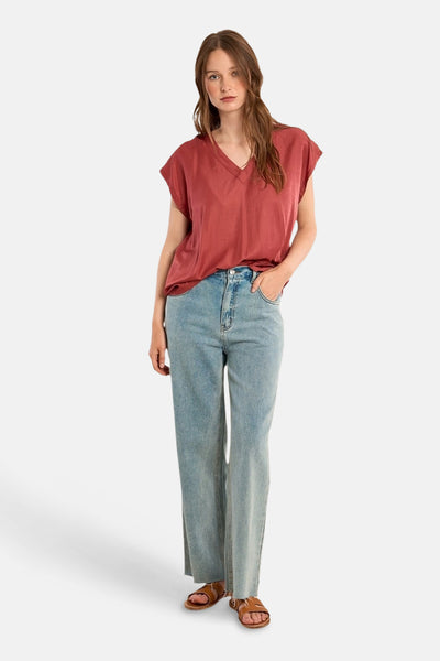 Rode blouse met korte mouwen van Molly Bracken, gedragen met een high-waisted jeans en bruine sandalen.