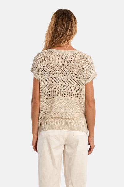 Zilveren Molly Bracken trui met een opengewerkt geometrisch patroon, gedragen met een crèmekleurige broek.