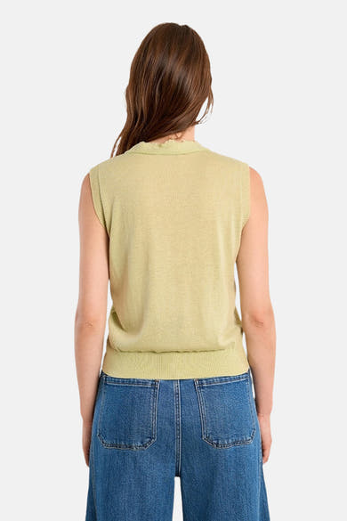 Gilet vert, de Molly Bracken, avec un col travaillé et porté avec un pantalon bleu ample.