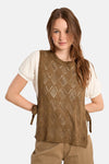 Pull ras du cou cognac de Molly Bracken, motif losanges ajourés, liens à nouer sur les côtés porté sur un t-shirt blanc.