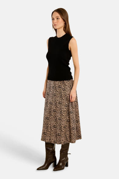 Pull col rond noir Molly Bracken porté avec une jupe imprimée léopard et des bottes marron.