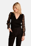 Black V-neck sweater with lace sleeves by Molly Bracken, worn with black trousers, side view