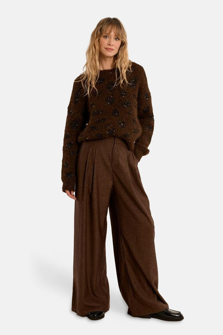 Brown O-neck sweater with black floral beading, soft textured knit, full-length front view, paired with wide-leg trousers and black loafers
