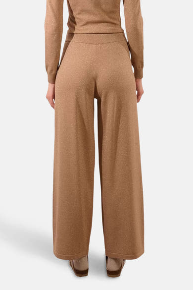 Beige pailletten wijde broek van Molly Bracken, van achteren getoond, met een bijpassend topje en sandalen.